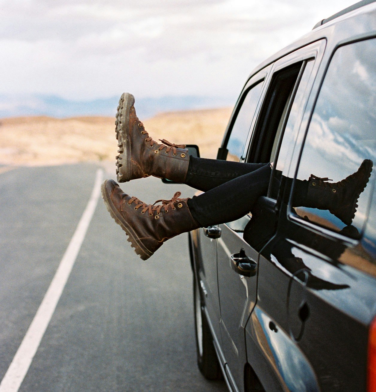 Boots hanging out of a moving car