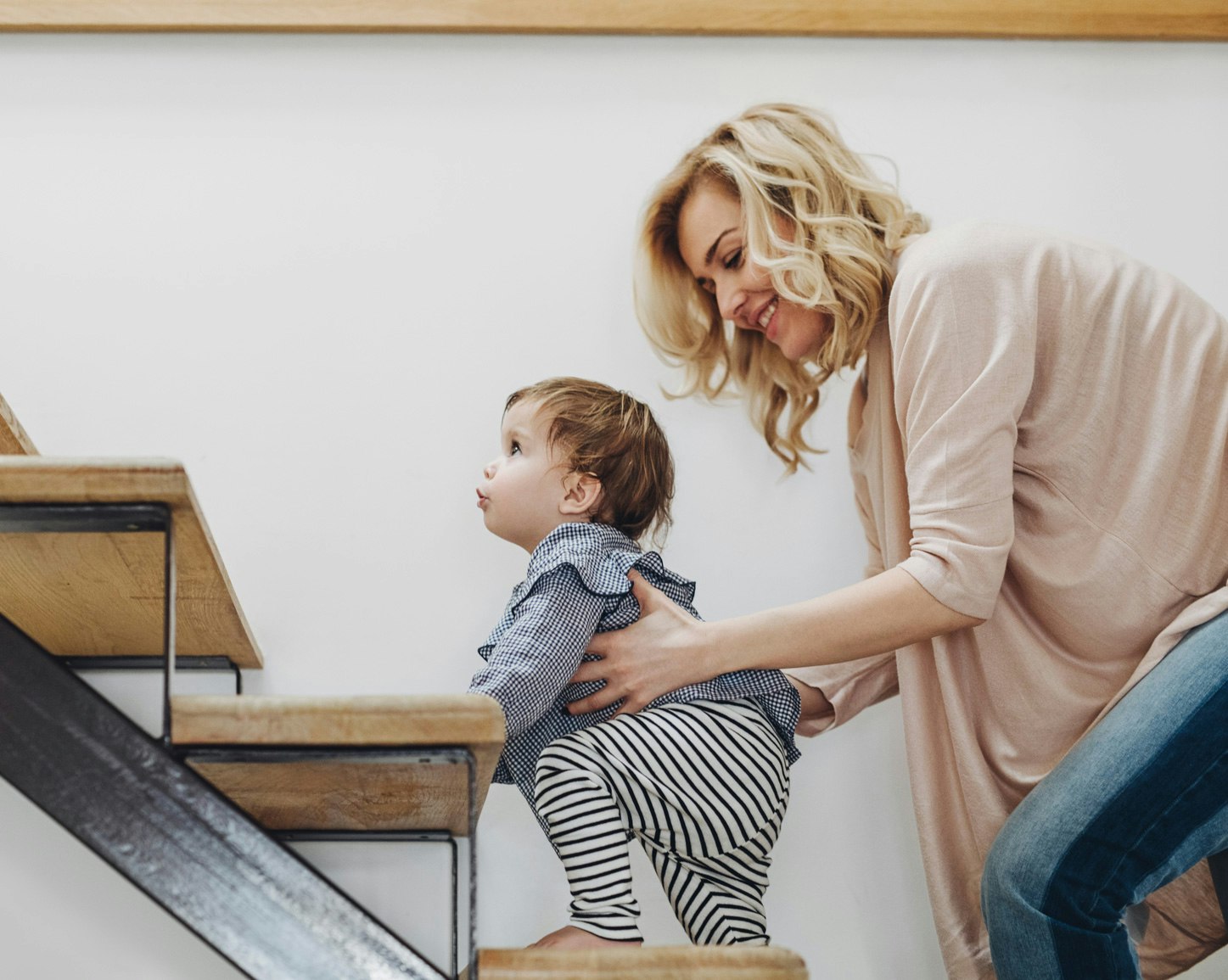 Mother helping her baby daughter climb up the stairs “